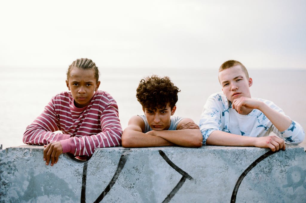 A diverse group of teenagers relaxing by a graffitied wall overlooking the ocean.