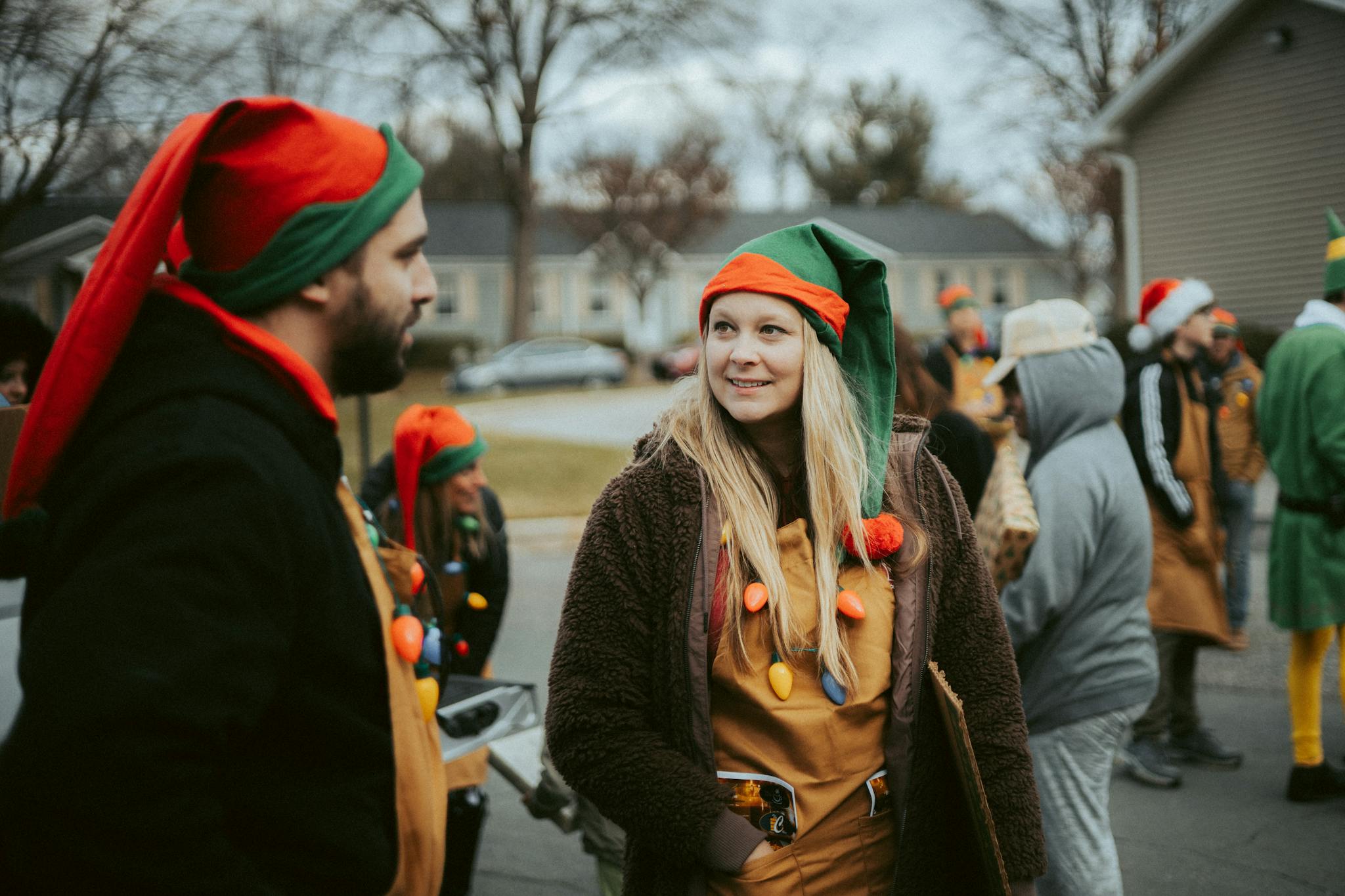A group of people dressed as elves celebrate outdoors, showcasing festive cheer.