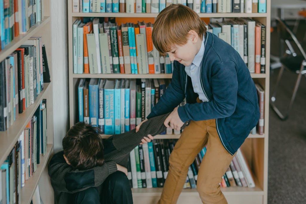 A young boy pulling another child's arm in a library setting, depicting a tense moment.