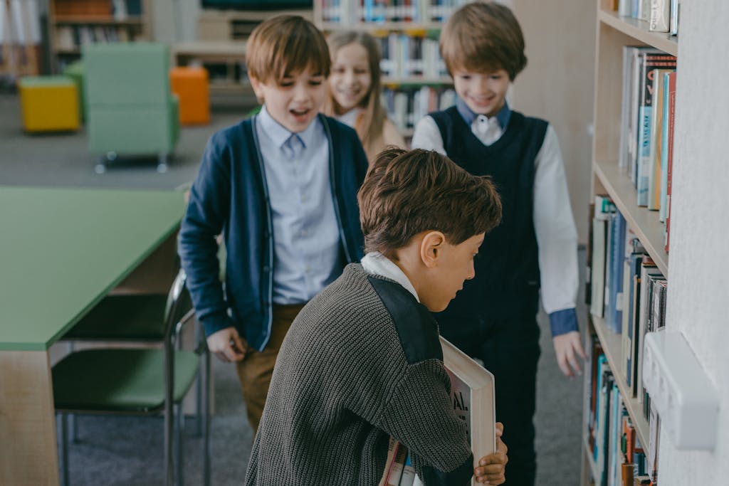 Group of children interacting by bookshelves in a school library environment.