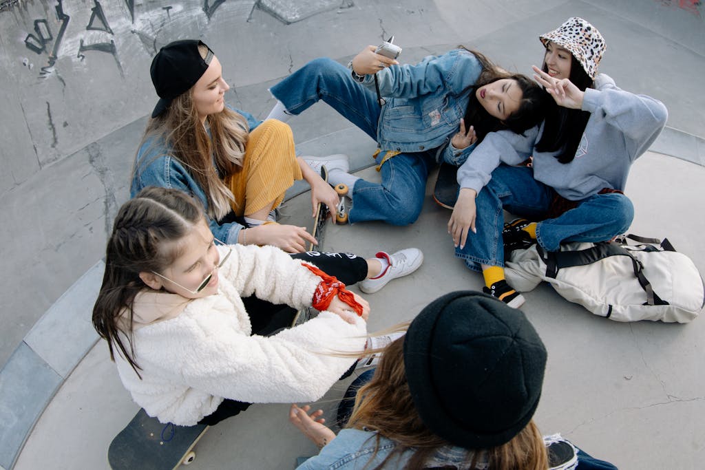 Group of teenagers relaxing and having fun at a skatepark with skateboards and vibrant clothing.