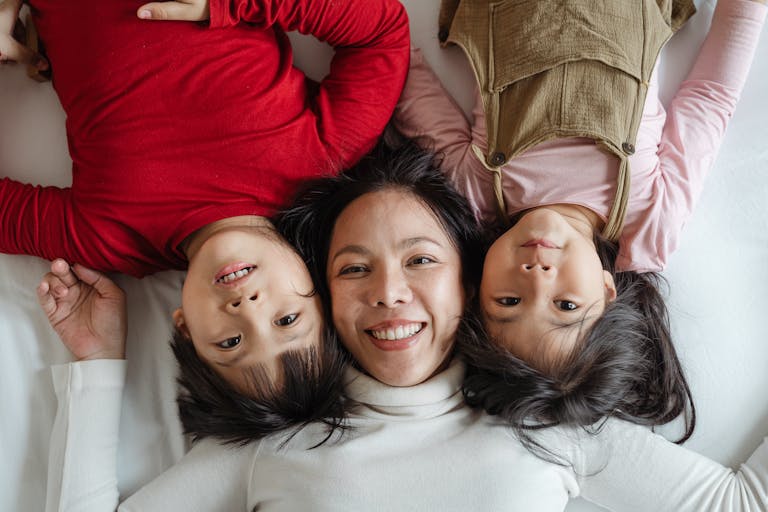 Joyous mother with her children lying on bed, capturing a happy moment of togetherness.