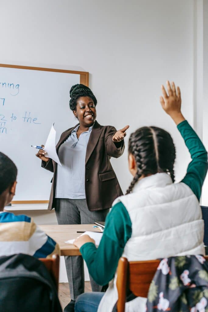 Student raising hand to participate as teacher engages