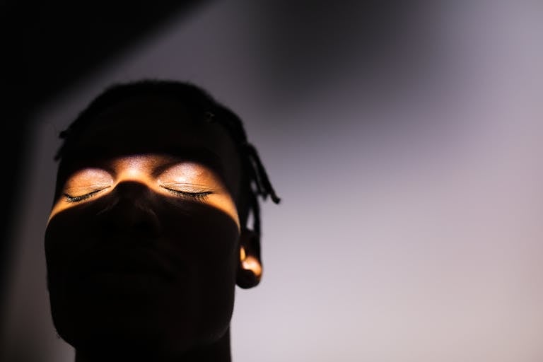 Silhouette of a man's face with dramatic lighting highlighting closed eyes.