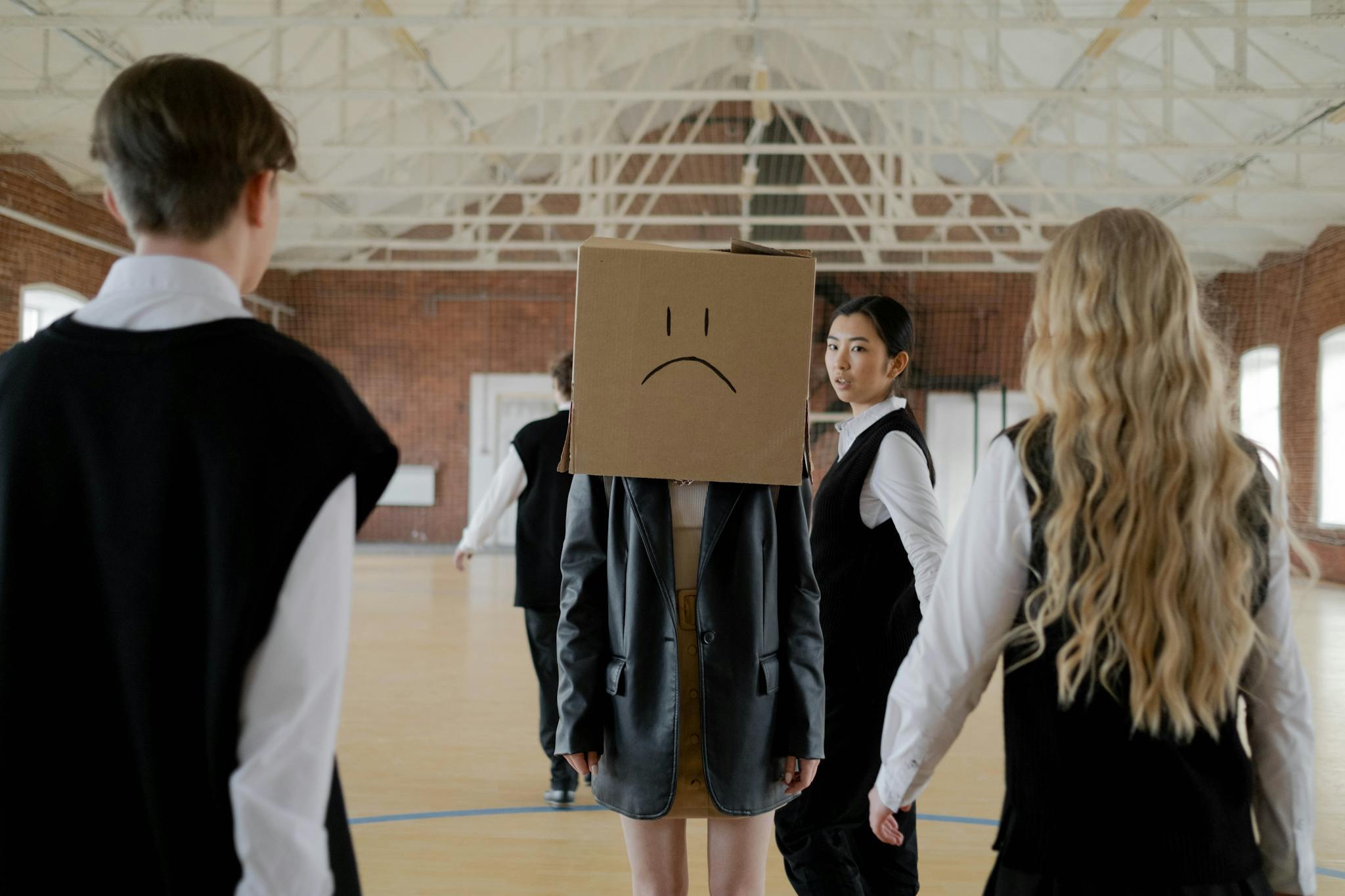Students in a school gym highlighting themes of bullying and peer pressure.