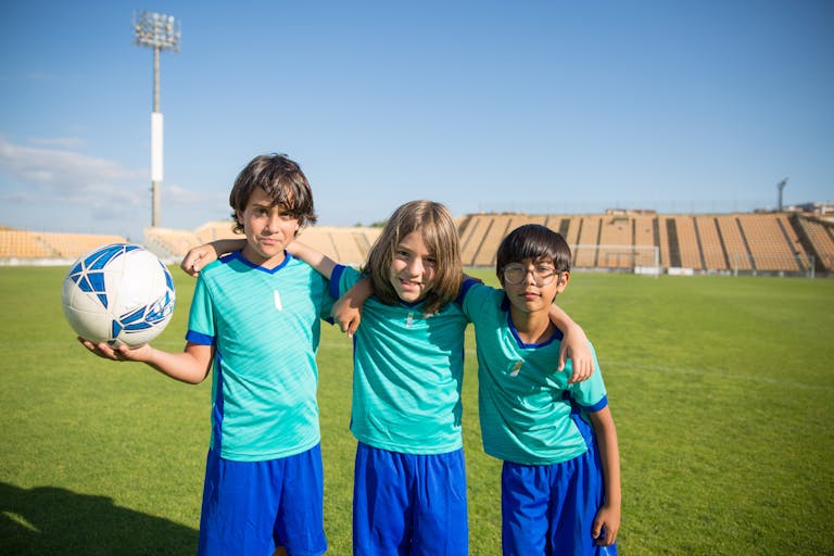 Three boys enjoying a sunny day playing soccer in a stadium in Portugal.